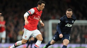 Ozil y Rooney disputan un balón