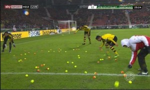Los aficionados del Borussia Dortmund lanzan pelotas de tenis al campo en protesta por los precios de las entradas.